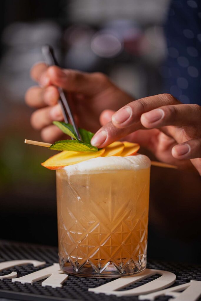 Bartender hand decorating alcoholic cocktail